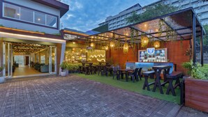 An outdoor seating area with tables and chairs, a bar with a sign, and a building entrance. - Beach Corridor Hotel & Spa with Free Airport Shuttle (Negombo)