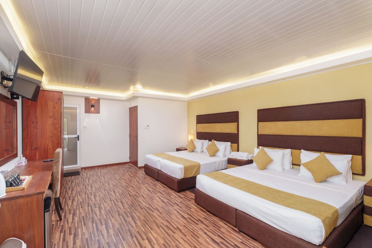 Una habitación de hotel con dos camas, un escritorio y una televisión.