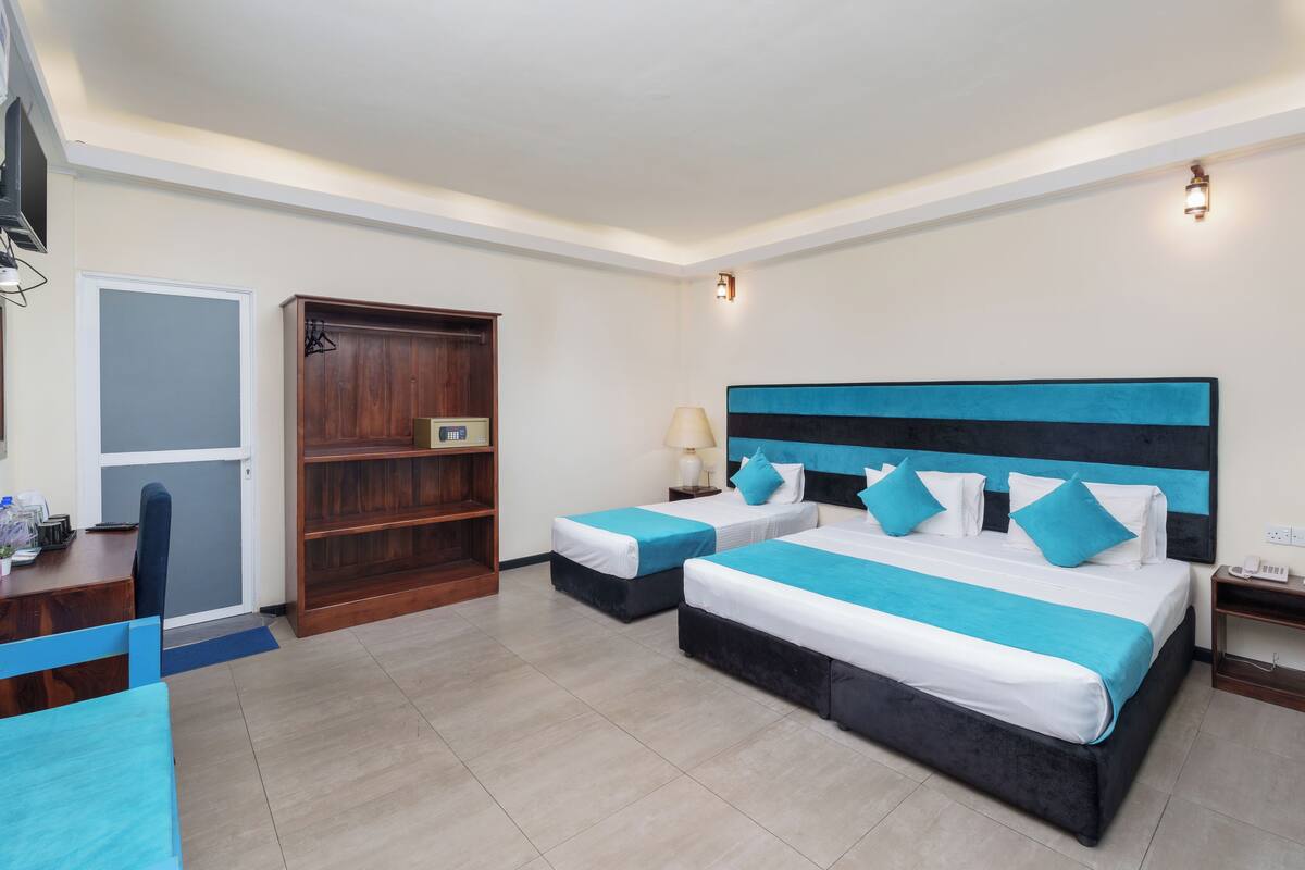 Habitación de hotel con dos camas, un escritorio, un armario y una mesita.
