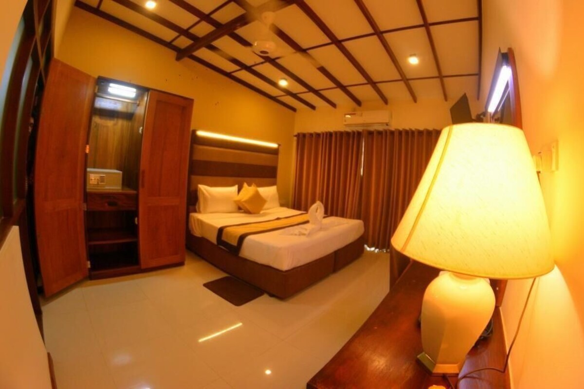 Habitación de hotel con cama, lámpara de noche y armario de madera.