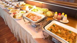 Un bufé con diversos platos, incluyendo un tazón grande de sopa, varias fuentes de comida y condimentos.