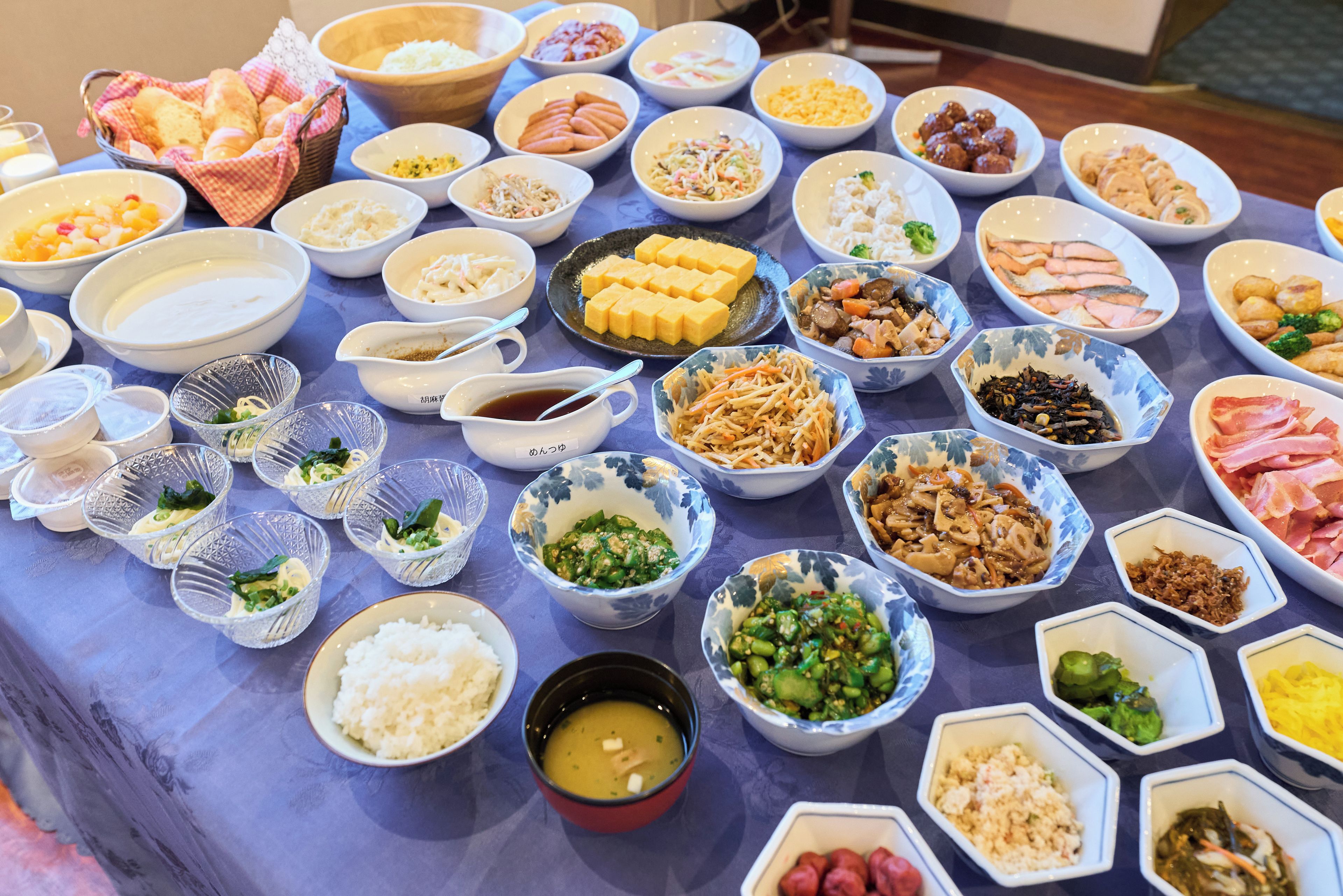 A table with various dishes and bowls of food, including rice, soup, and different types of meat and vegetables.