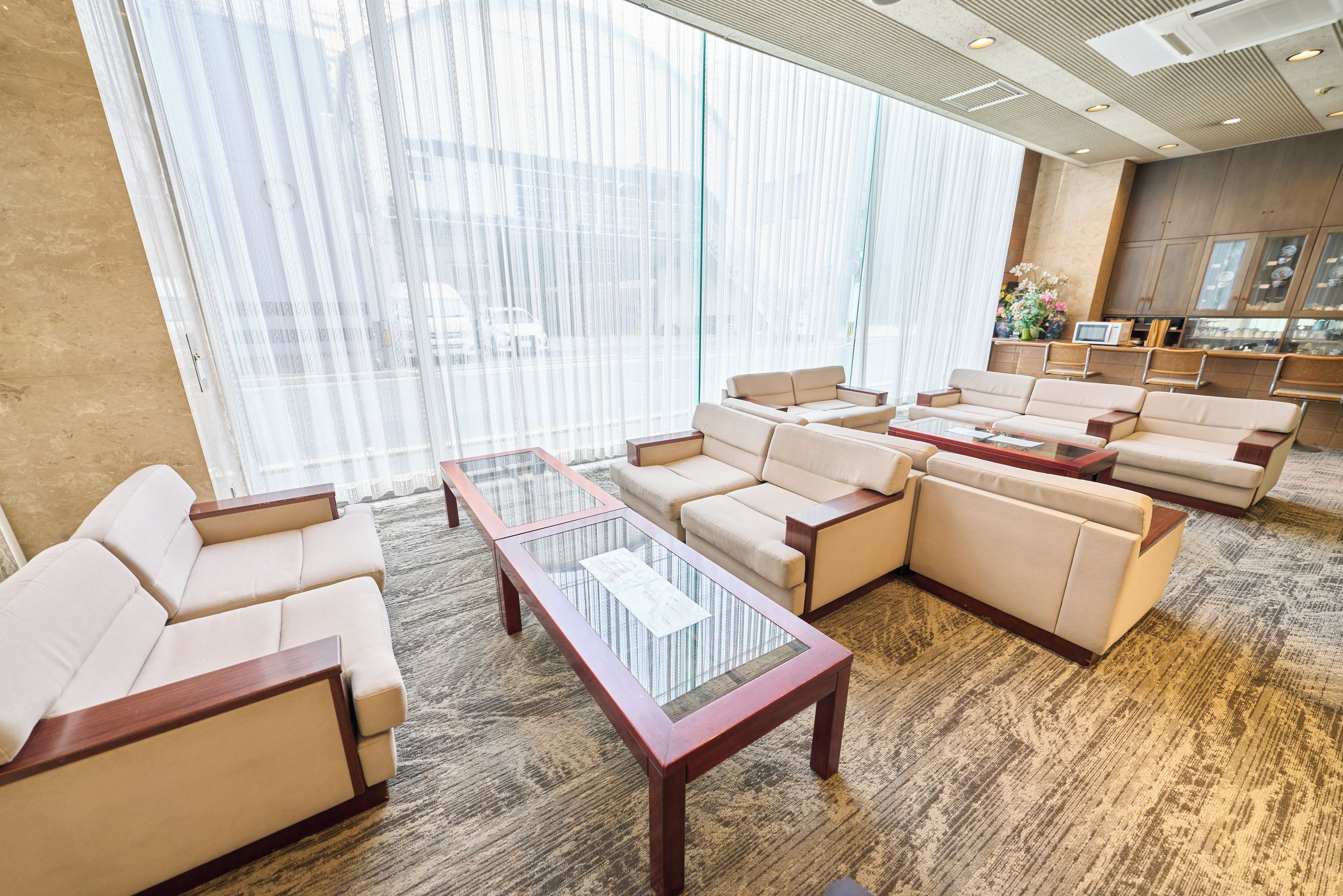 A hotel lobby with a seating area featuring sofas and a glass-top coffee table.