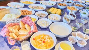 A table with various dishes, including a bowl of fruit salad, a plate of bread, and several small bowls of condiments.