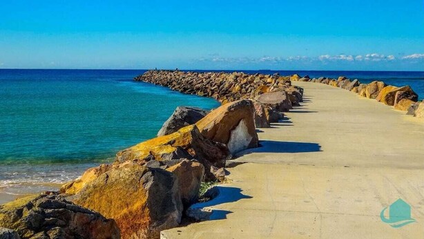 A concrete pathway along a rocky coastline with clear blue water. - Driftwood in Blacksmiths - free WIFI, close to the beach (Blacksmiths)