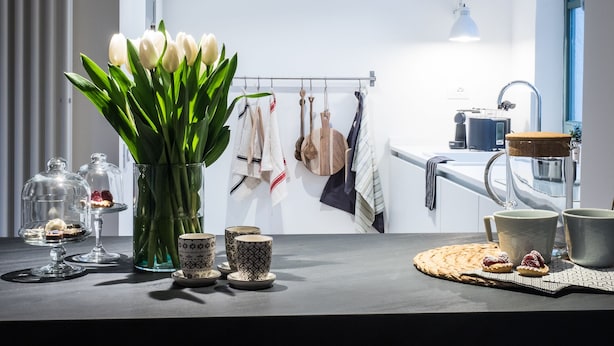 A modern kitchen with a large window, a vase of white tulips, and various kitchen items on the counter. - Le Logge apartment (Parma)