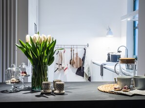 Eine moderne Küche mit einem großen Fenster, einer Vase mit weißen Tulpen und verschiedenen Küchenutensilien auf der Arbeitsfläche.