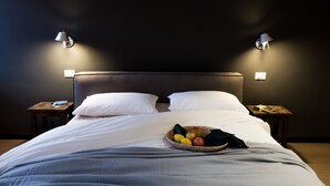 A neatly made bed with white linens, a fruit bowl on the bed, and two bedside tables with lamps. - Le Logge apartment (Parma)
