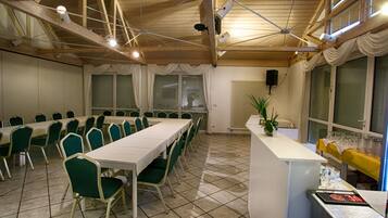 A conference room with a long table, green chairs, a white counter with glasses, and a ceiling fan.