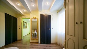 Un pasillo con suelo de madera, un espejo y una puerta.