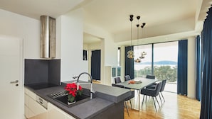A modern kitchen with a built-in island, a dining area with a table and chairs, and a view of the outdoors.