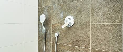 Ein Duschbereich mit Handbrause und am Wand montiertem Wasserhahn.
