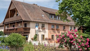 A traditional building with a sloped roof, multiple windows, and balconies adorned with flowers. - Gasthof Zur frohen Einkehr (Ohrenbach)
