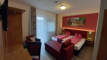 A hotel room with a bed, a desk, a chair, and a window with curtains.