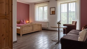 A bedroom with a wooden bed, a small round table, a sofa, and a chair. - Gasthof Zur frohen Einkehr (Ohrenbach)