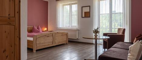 A bedroom with a wooden bed, a small round table, a sofa, and a chair.