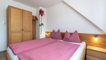 Une chambre avec un grand lit, une armoire en bois et un luminaire fixé au mur.