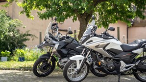 Two motorcycles parked on a cobblestone street with a building and trees in the background. - Gasthof Zur frohen Einkehr (Ohrenbach)