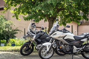 Two motorcycles parked on a cobblestone street with a building and trees in the background. - Gasthof Zur frohen Einkehr (Ohrenbach)