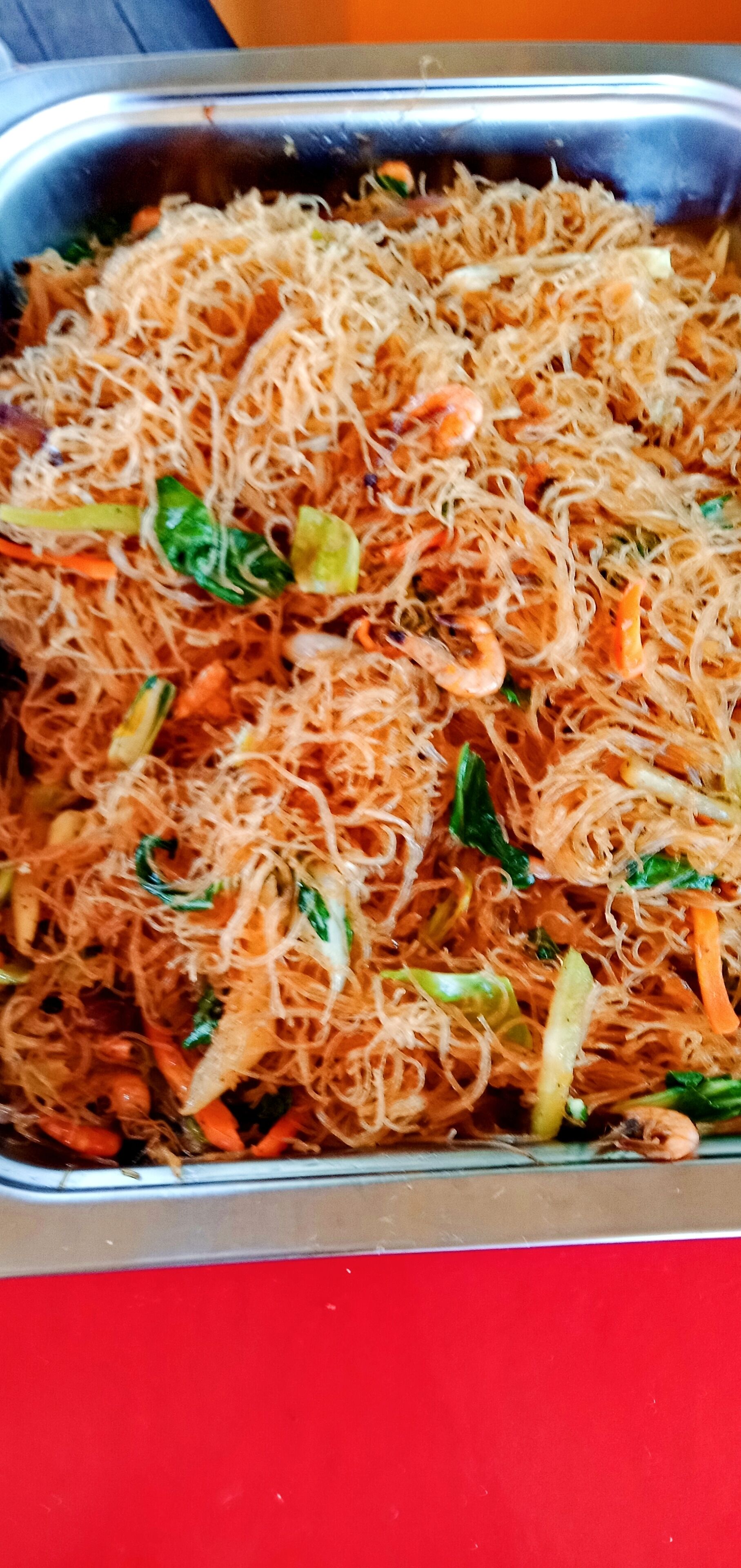 A close-up of a dish with noodles, vegetables, and shrimp.