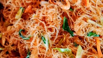 A close-up of a dish with noodles, vegetables, and shrimp.
