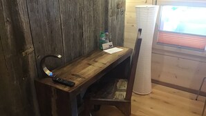 A wooden desk with a remote control, a bottle, and a piece of paper. - La Grange (Charmey)
