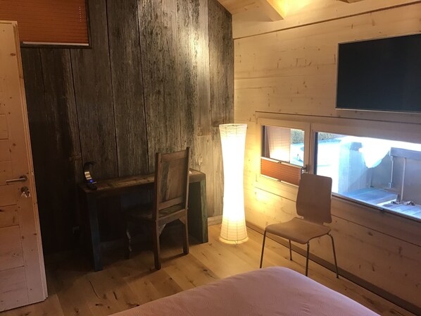 A room with a bed, a desk, a chair, a large window, and a TV mounted on the wall. - La Grange (Charmey)