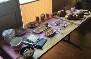 A table with various food items including bread, pastries, and condiments. - La Grange (Charmey)