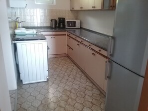 Una cucina compatta con frigorifero, microonde e un piccolo lavandino.