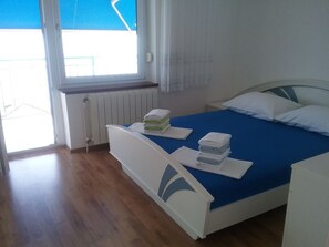 Een slaapkamer met een bed, een raam en een radiator.