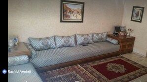 A living room with a sofa, a small table, a cabinet, and a rug. - Impeccable 2-bed Apartment (Temara)