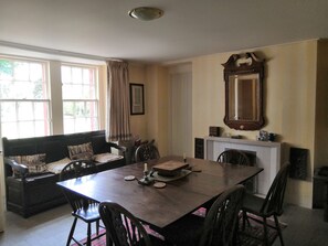 A dining room with a large table, chairs, a sofa, and a fireplace. - Beautiful 8-bed House in Angus (Kirriemuir)
