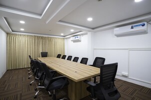 Una sala de conferencias con una larga mesa de madera, sillas negras y un equipo de aire acondicionado en la pared.