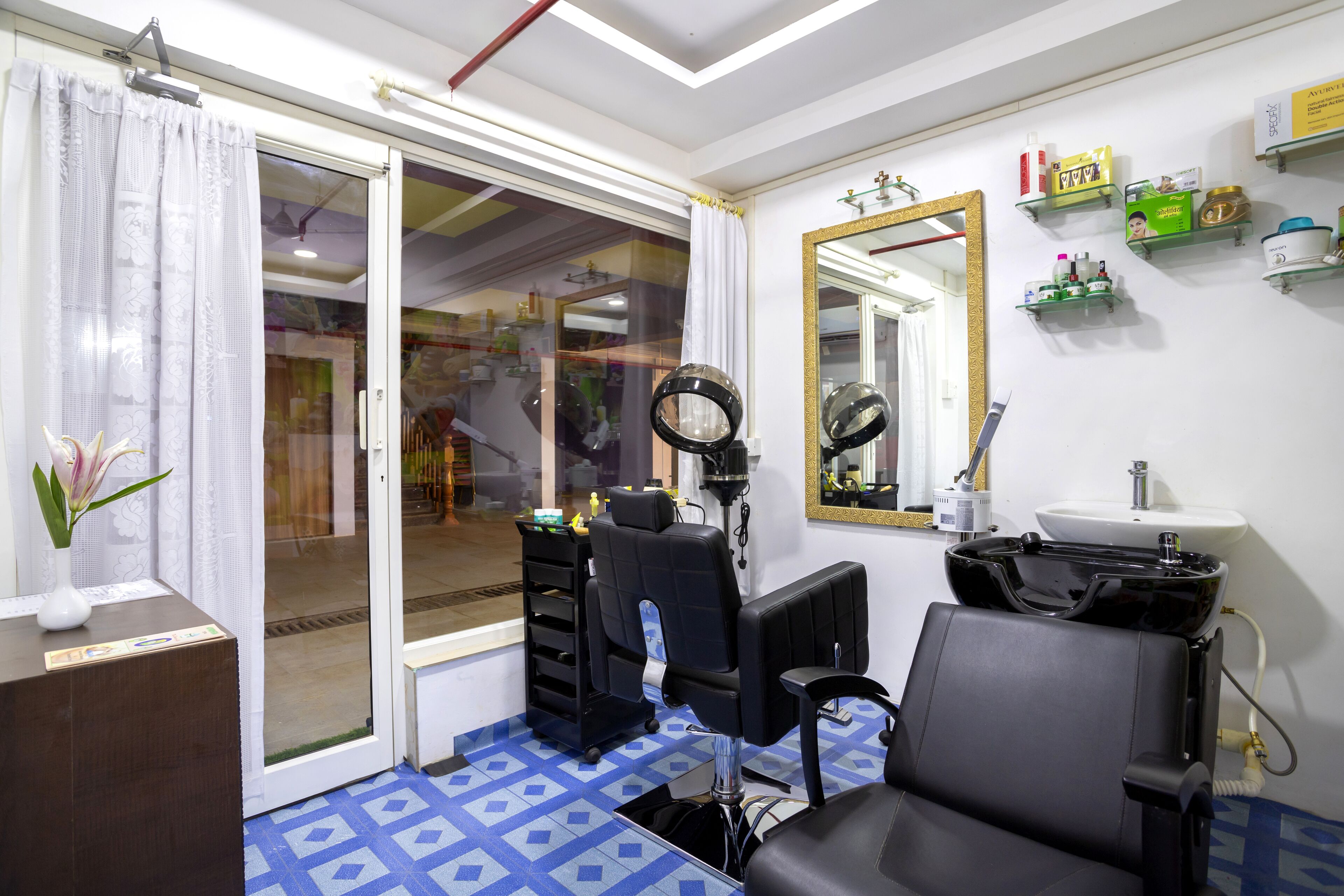 A hair salon with a reception desk, a mirror, a sink, and a chair.