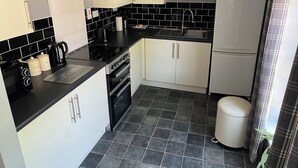 A compact kitchen with a stove, sink, and refrigerator. - Large 2-bed House Derbyshire off Chatsworth rd (Chesterfield)