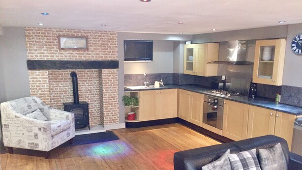 A modern kitchen with wooden cabinets, a black stove, and a built-in oven. - Large 2-bed House Derbyshire off Chatsworth rd (Chesterfield)