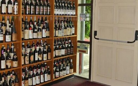 A wine cellar with shelves of wine bottles and a welcome mat with "happy new year" text.
