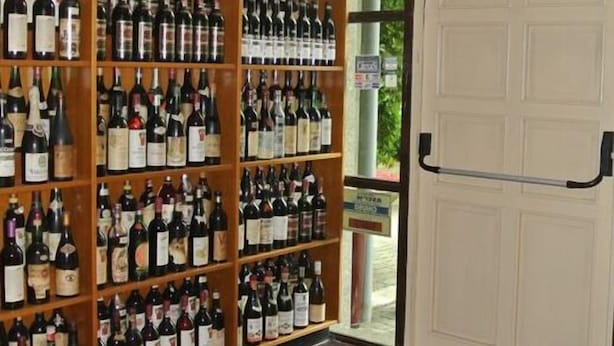 Una cava de vinos con estantes llenos de botellas y un felpudo con la inscripción 'Feliz Año Nuevo'.