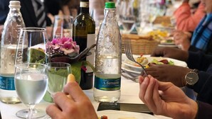Una mesa de comedor con varias botellas, vasos y una ensalada.