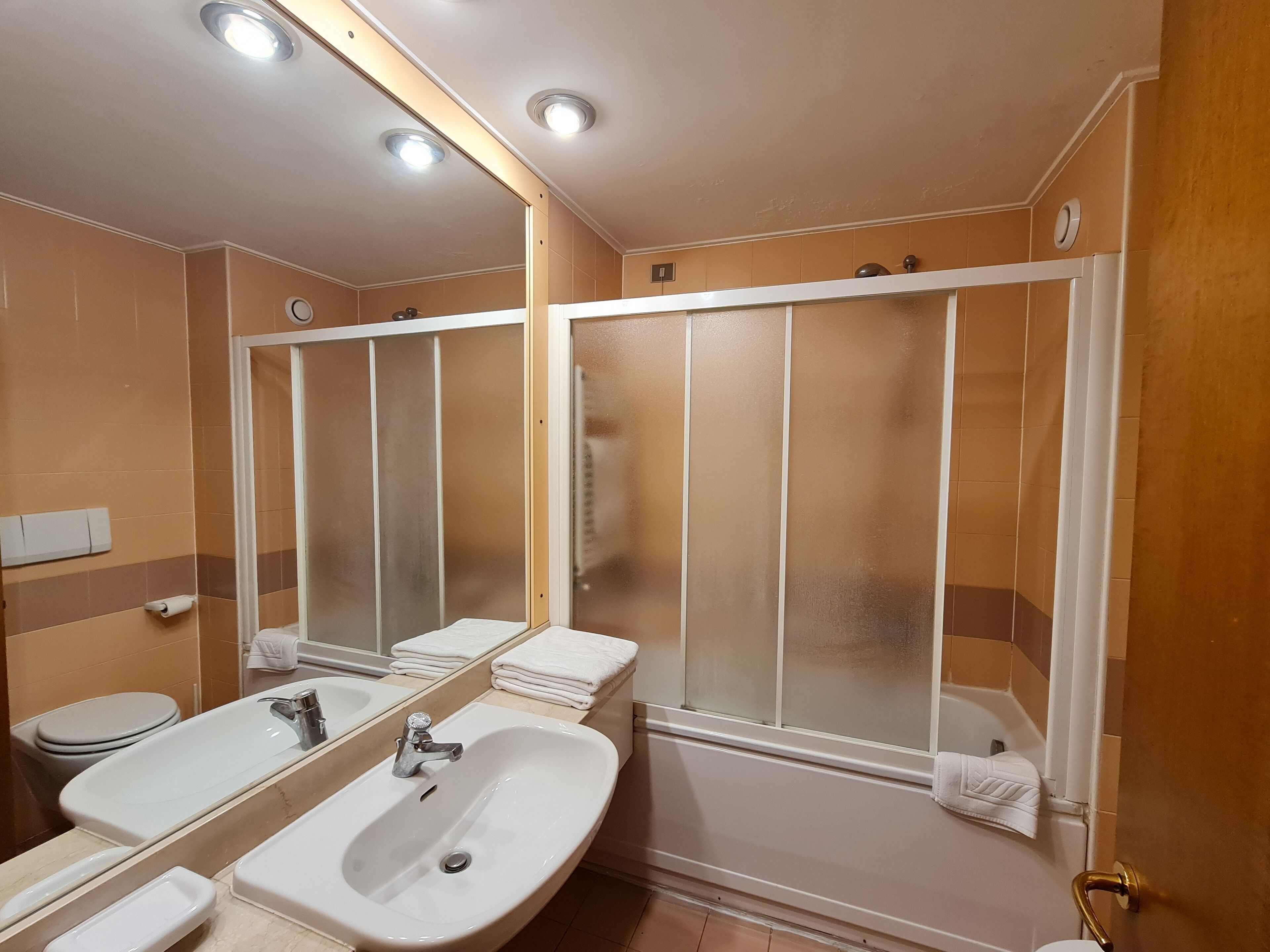 A bathroom with a sink, mirror, and a shower stall.