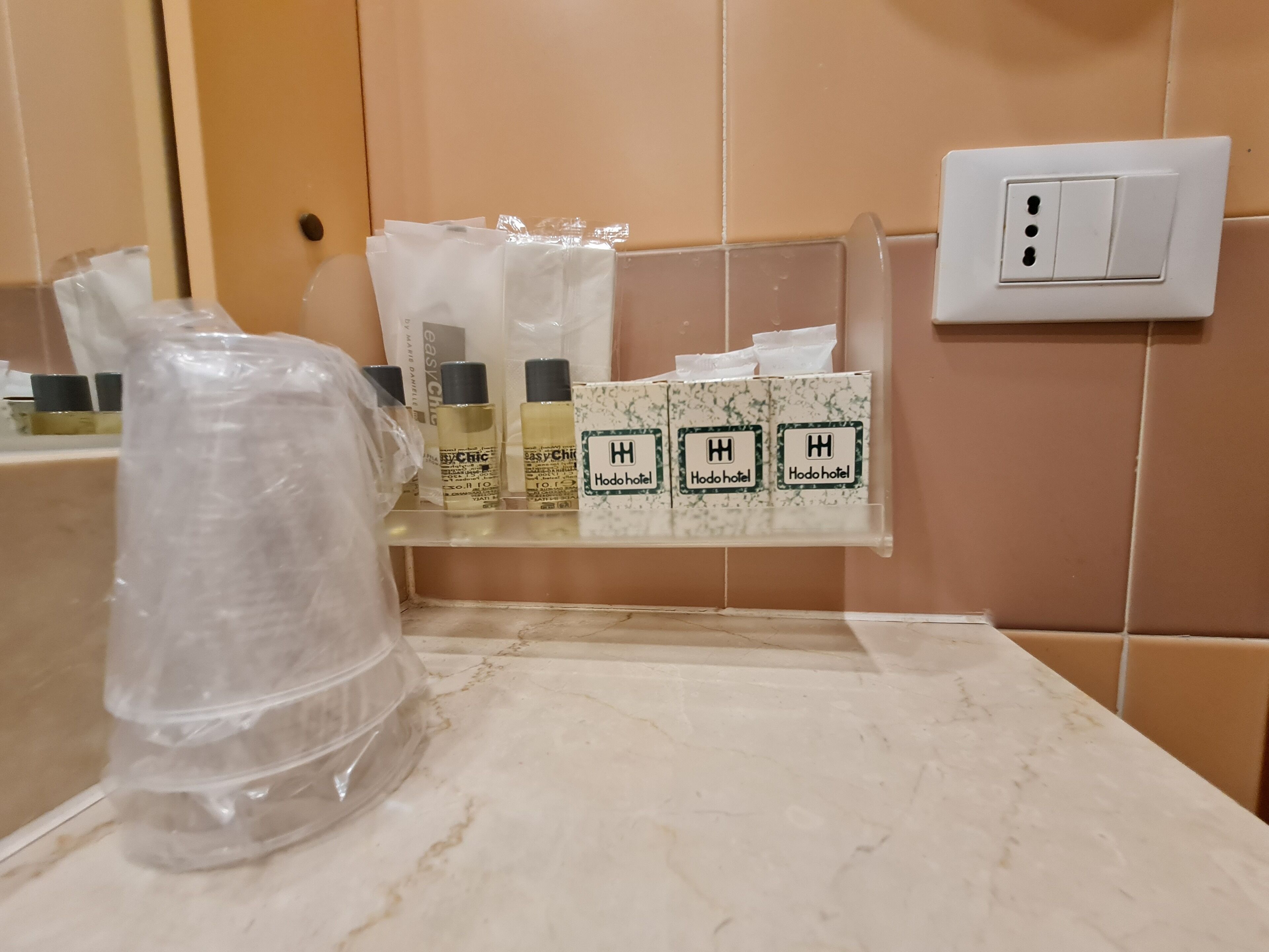 Un baño con encimera de mármol, un estante con artículos de aseo y una bolsa de plástico.