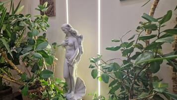 A statue of a woman in a garden setting with various plants around.