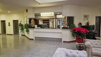 Un área de recepción con mostrador, un piano y un espacio de estar con un sofá capitonado.