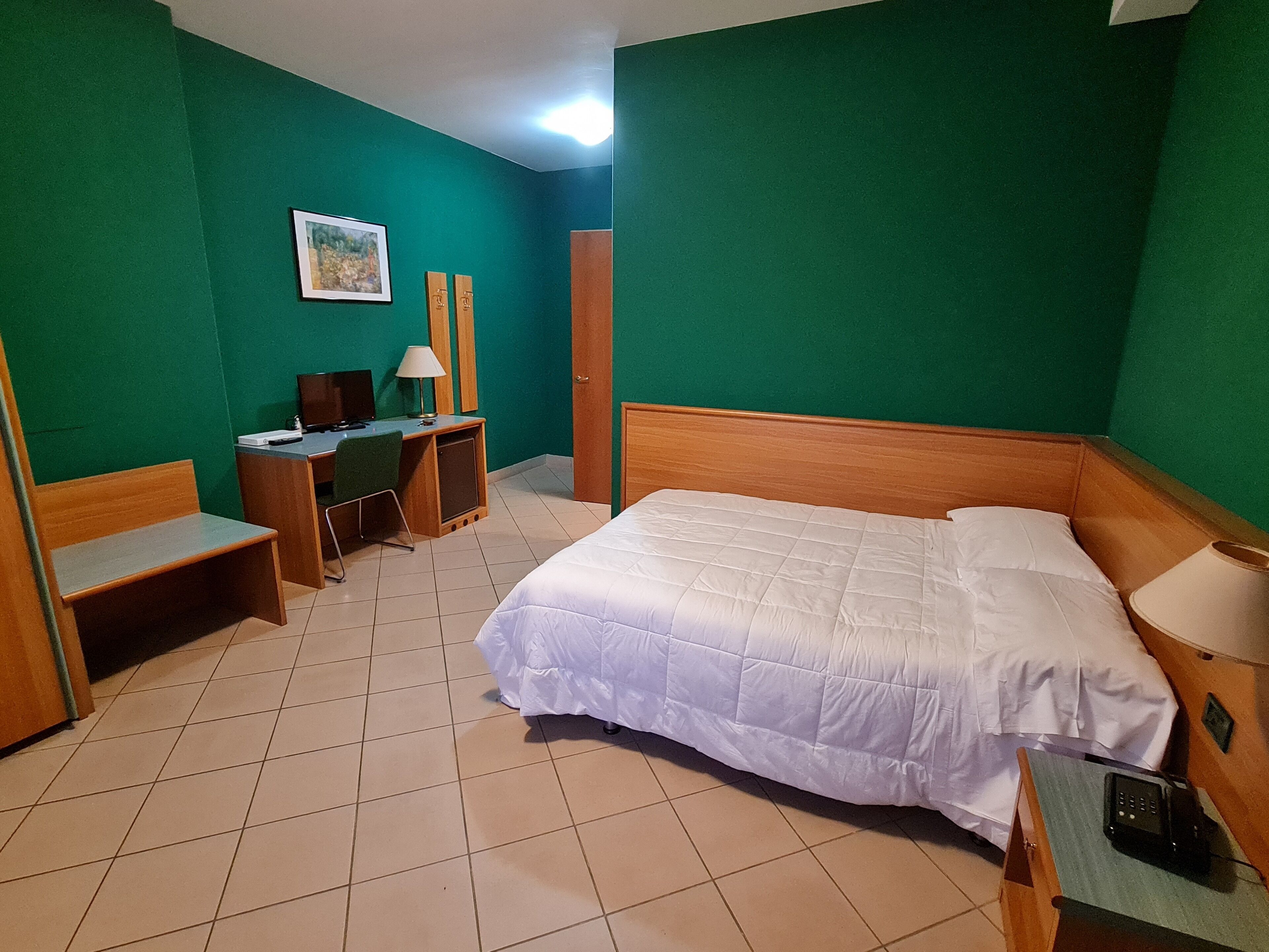 Une chambre d’hôtel comprenant un lit, un bureau, une chaise et un petit placard.