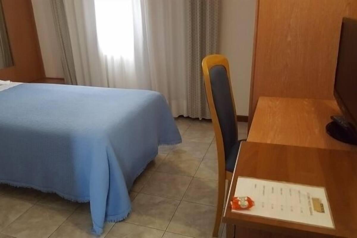 A hotel room with a bed, a desk, and a chair.