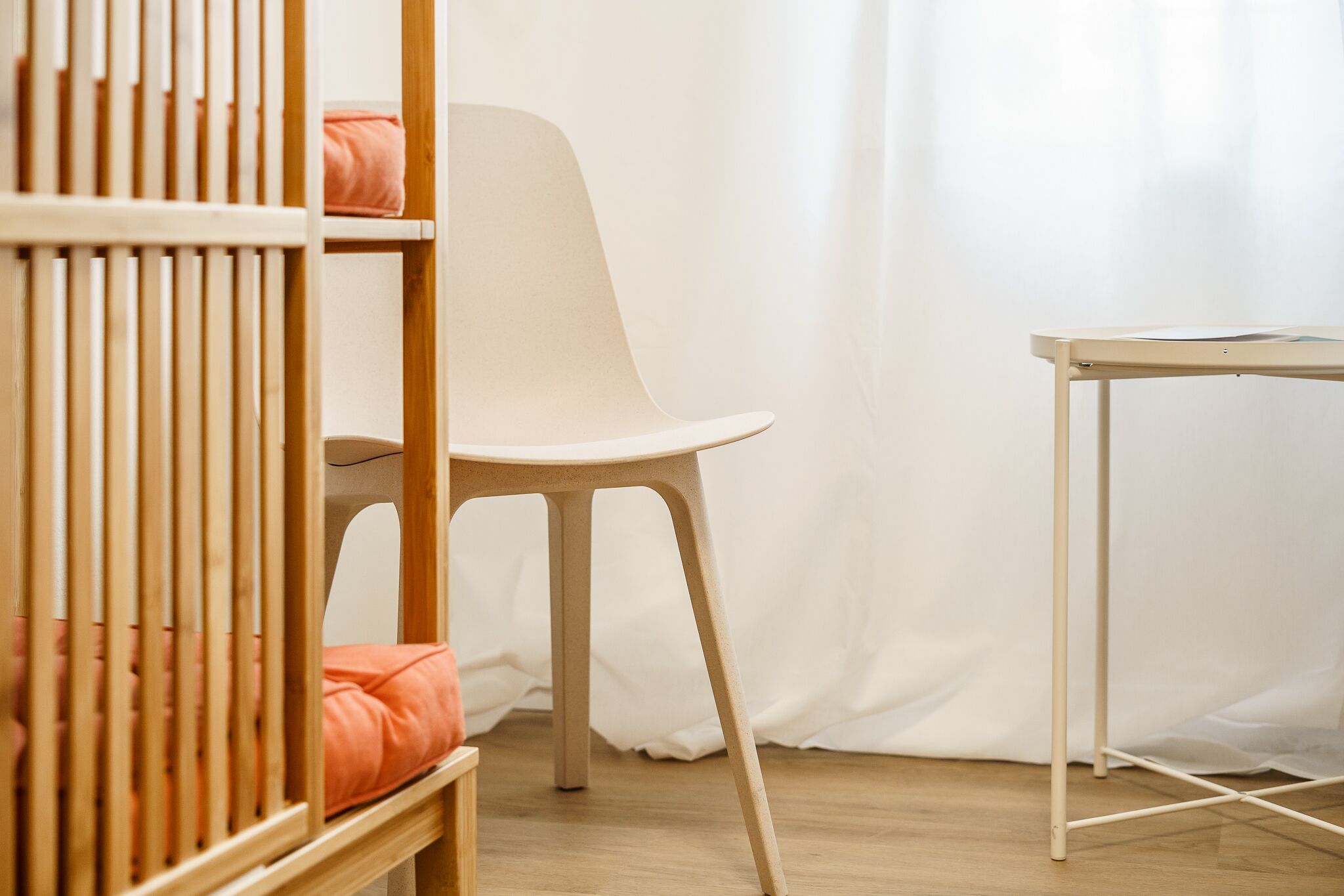 A room with a crib, a chair, and a small table.