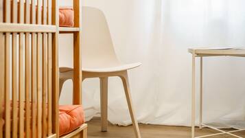 A room with a crib, a chair, and a small table.