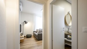 Ein heller, moderner Flur führt in einen Wohnbereich mit Sofa, Lampe und Spiegel.