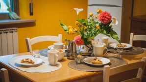 Une table à manger avec des assiettes remplies de nourriture, des tasses et une cafetière.