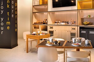 Una cocina moderna con armarios de madera, una mesa de comedor dispuesta para el desayuno y una cafetera.